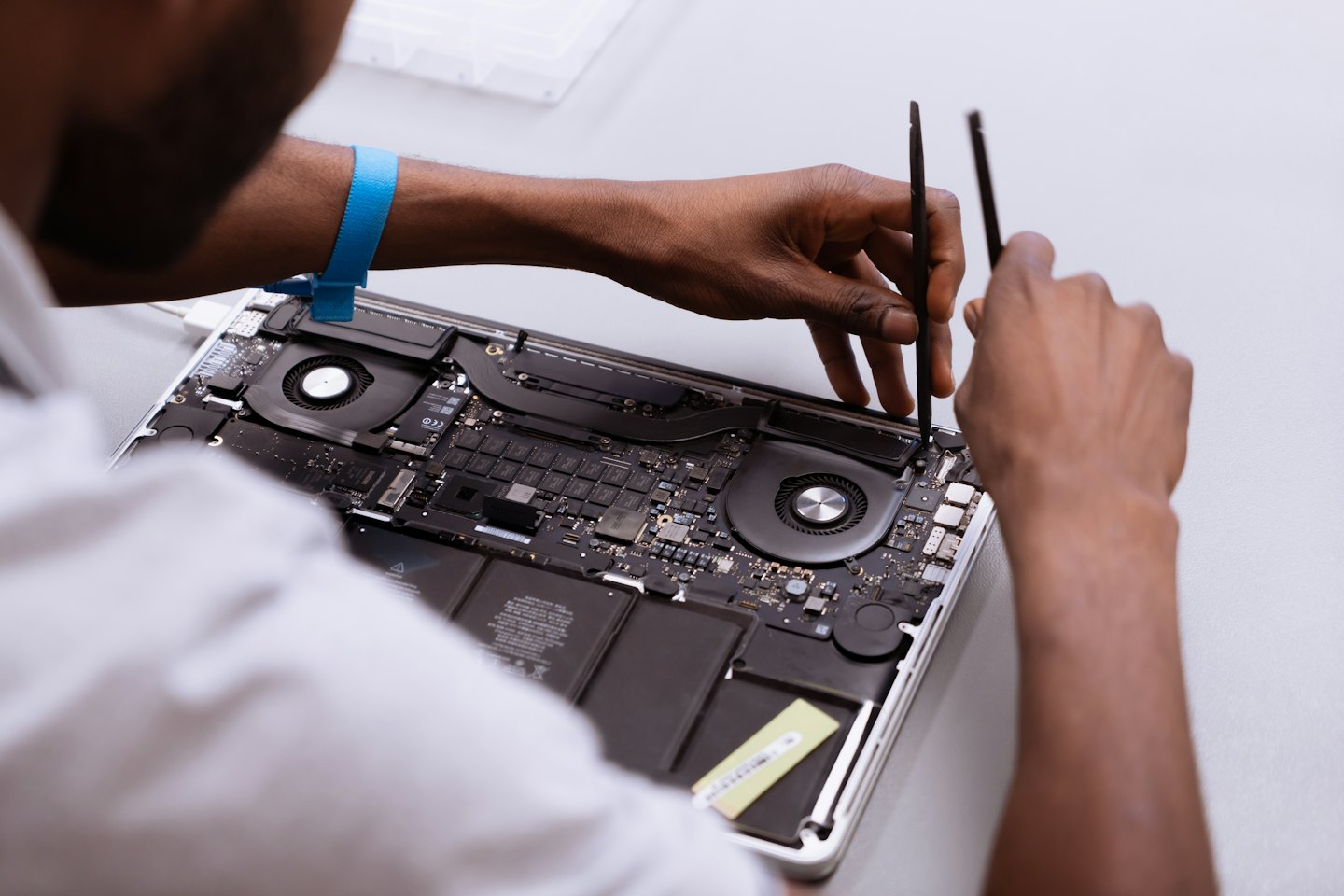 Technician repairs open laptop with small tools.