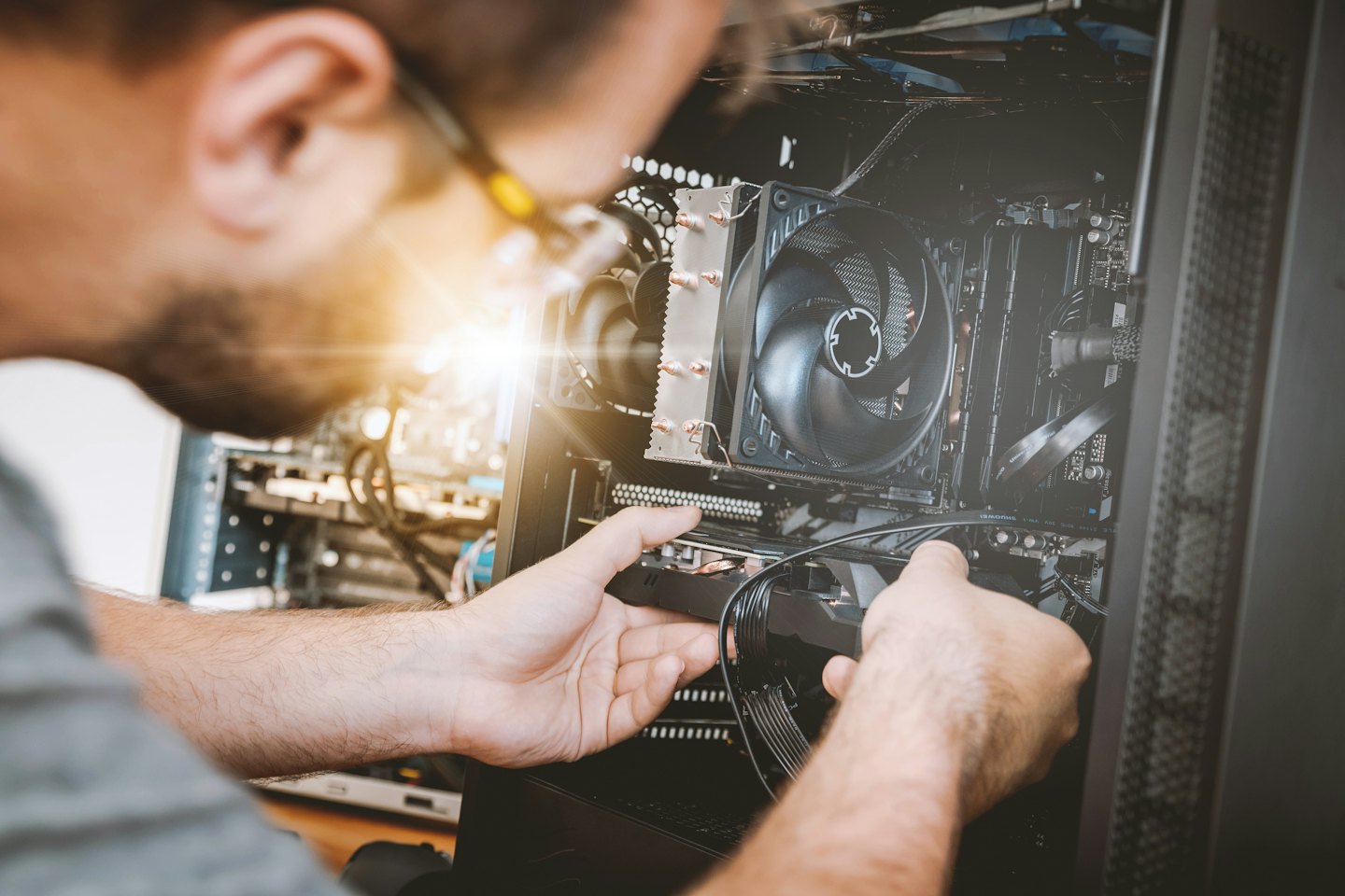 Hands installing components inside an open desktop computer.